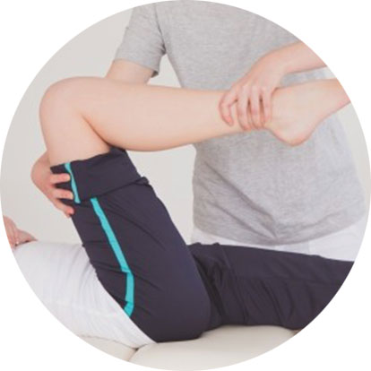 Der Physiotherapeut winkelt das Bein des Patienten an.